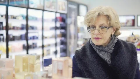A middle-aged woman is choosing perfume in a store Stock Footage 84908341