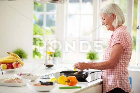 Middle aged woman cooking meal in kitchen Stock Photos