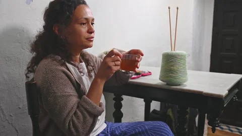 Middle aged woman drinking tea while knitting at home Video stock 275852809