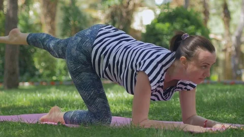 A middle-aged woman on the grass does a morning sports exercises Stock Footage 84176489
