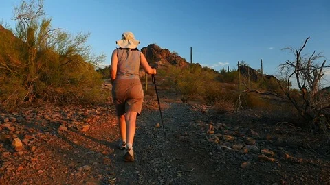 A middle-aged woman hiking in the desert at sunset Stock Footage 80782653