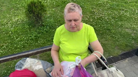 Middle-aged woman in neon yellow t-shirt sitting on park bench  Vídeo Stock 338361553