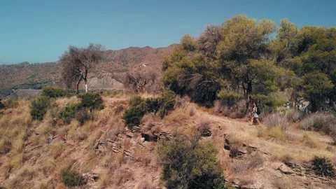 Middle-aged woman in red jacket and hiking boots walks on a dry Stock Footage 345669154