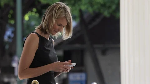 Middle-aged woman smiling while using a smart phone. 스톡 동영상 88368893