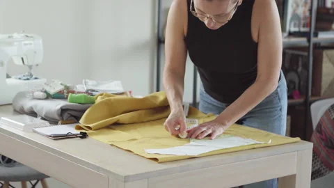 Middle aged woman tailor precisely sewing clothing patterns in small business fa Vidéo 307631434