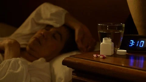 Middle aged woman taking sleeping pills on bedside table Stock Footage 125171984