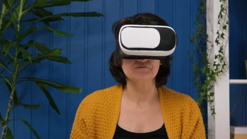 Middle aged woman using innovative technology vr glasses for play games and Stock Footage 183910693