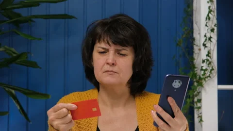 Middle aged woman using mobile phone application and credit card for online Stock Footage 171481204