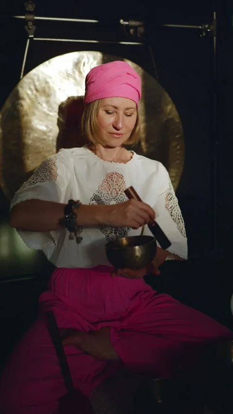Middle aged woman using singing bowl in sound healing therapy indoors. Stock Footage 276956230