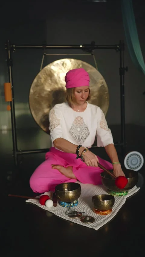 Middle aged woman using singing bowls in sound healing therapy indoors. Stock Footage 276957611