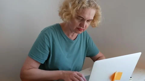 Middle aged woman using smart phone and laptop  at home, female using smart.. Stock Footage 253706424
