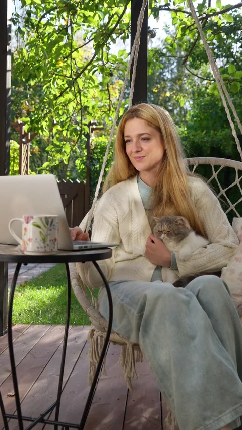 Middle aged woman working remotely with laptop and cat Stock Footage 317979582