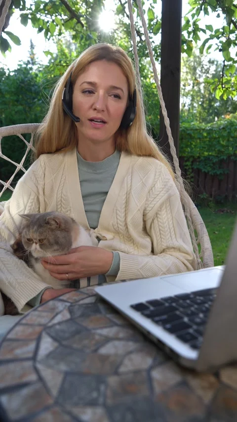 Middle aged woman working remotely with laptop and cat Stock Footage 317980760