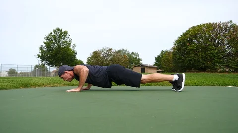 Middle aged young man doing push ups in the park on a summer day, 4k, 60fps Stock Footage 115185133