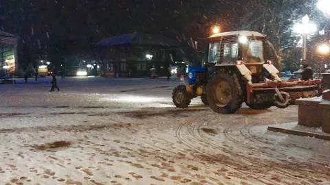 In the middle of the city square there is a tractor with a snow brush. Stock Footage 99556519