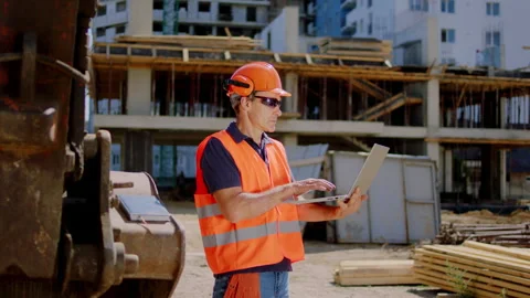 In the middle of construction site builder using laptop to check the plan of Stock Footage 152081264