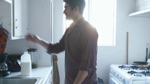 Middle eastern bachelor opens cupboard in apartment kitchen Stock-Footage 89235392