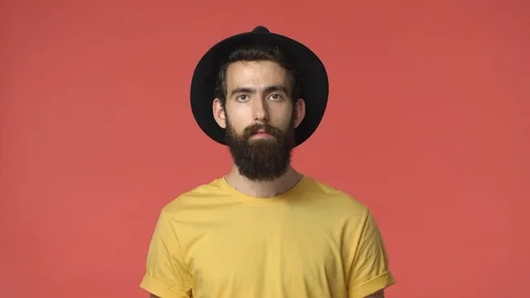 Middle-eastern bearded man in black hat, yellow t-shirt, standing casually red Stock Footage 115779409
