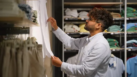 Middle eastern customer choosing clothes in fashion store with discount Stock Footage 314026423