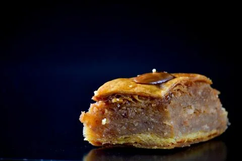 Middle Eastern dessert called mabroume or bahlava isolated on black backgroun Stock Photos