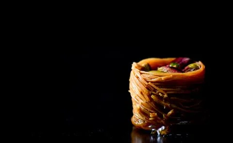 Middle Eastern dessert called mabroume or burma isolated on black background. Stock Photos
