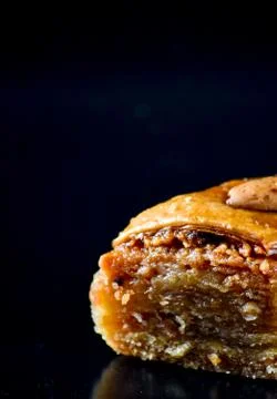 Middle Eastern dessert called mabroume or bahlava isolated on black backgroun Stock Photos