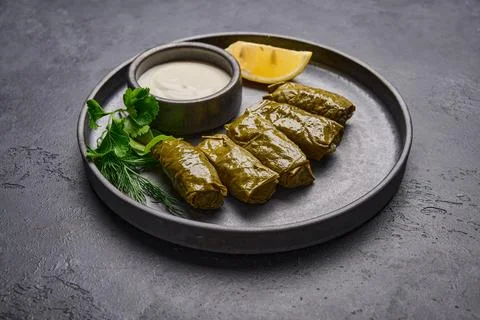Middle Eastern dish dolma or sarma, with parsley, saucepan with sour cream and Stock Photos