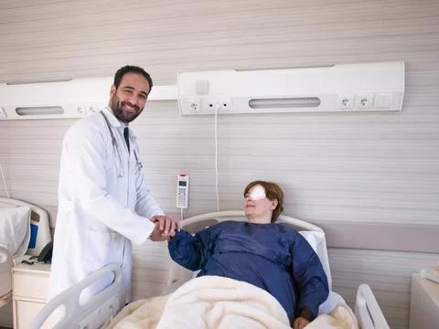 Middle Eastern doctor shaking hands with recovering female patient in hospital Stock Photos
