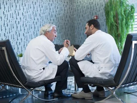 Middle Eastern doctors in white coats discussing patient care during a clinical Stock Photos