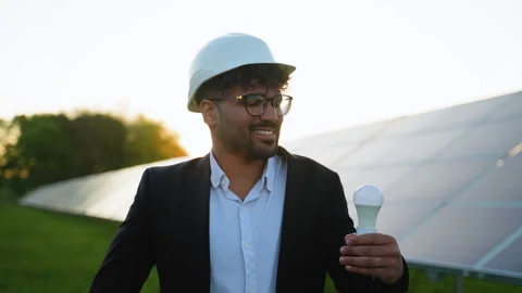 Middle eastern engineer holding light bulb in solar panel farm Stock Footage 314410329