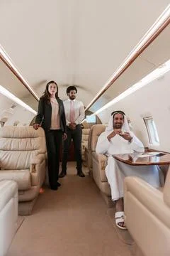 Middle Eastern executive relaxing with colleagues aboard a luxury private jet Stock Photos