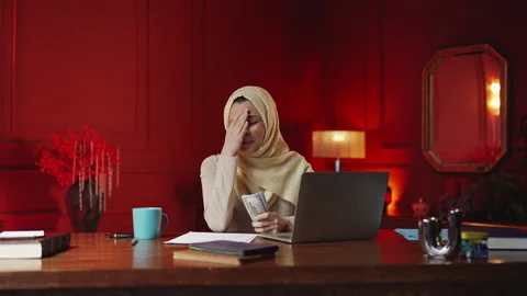 Middle Eastern freelancer counts money by laptop, disappointed by low profit Stock-Footage 343986178