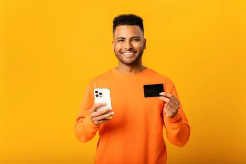 Middle-eastern happy man is ordering food online, male paying for long-awaited Stock Photos