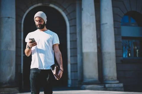 Middle Eastern hipster guy making online booking and banking via cellphone Stock Photos
