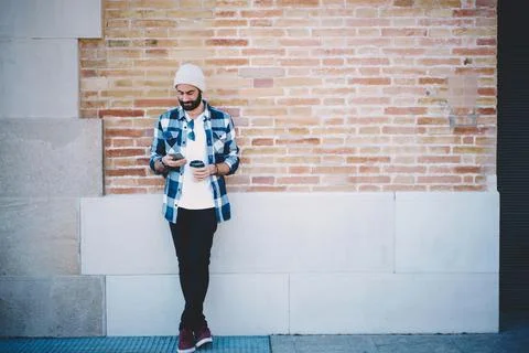 Middle Eastern hipster guy with takeaway cup using smartphone technology for Stock Photos