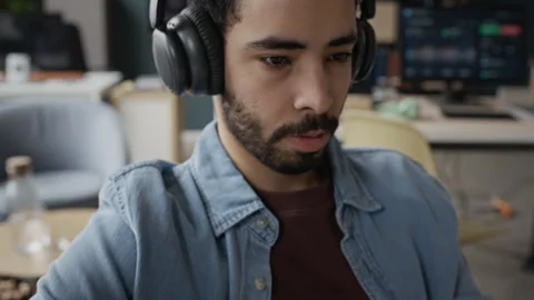 Middle Eastern Male Programmer Wearing Headphones Typing on Keyboard in Office Video stock 337476901