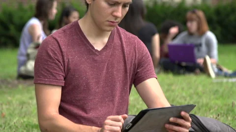 A Middle Eastern male student, uses a digital tablet outside. Stock Footage 44117138