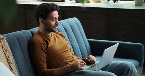 Middle Eastern Man Engages in Video Call with Laptop on Sofa Stock Footage 254442305