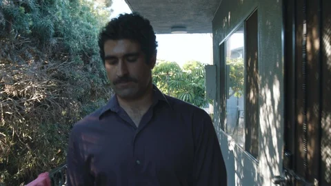 Middle eastern man pacing down apartment walkway at affordable housing Stock Footage 89231688