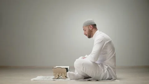 Middle Eastern man praying close-up, reading quran on floor, islamic religion Stock Footage 178569243