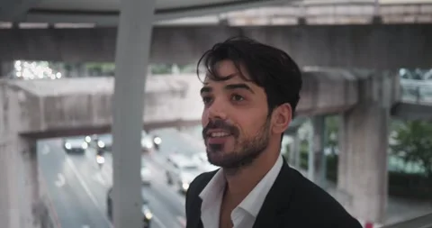 Middle Eastern man in suit strides energetically across bridge over highway Stock-Footage 275871563