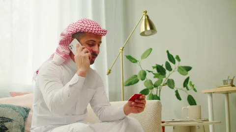 Middle eastern man using credit card and smartphone. Male person talking on Stock Footage 201273703