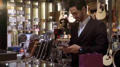 A Middle Eastern Man Using Mobile Phone To Purchase Product Stock Footage 120380009