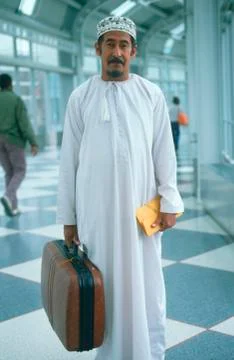 Middle Eastern man wearing white robes holding suitcase, JFK Airport, New York Stock Photos