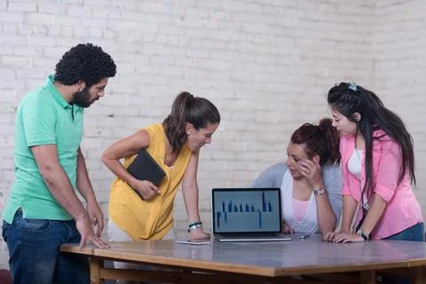 Middle Eastern startup team collaborating around laptop with data charts in Stock Photos