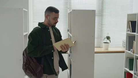 Middle Eastern Student Choosing Book from Library Shelf Stock Footage 337476667