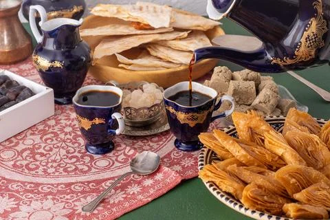 Middle Eastern Sweets and Coffee Service. Pouring coffee from a cobalt blue.. Stock Photos
