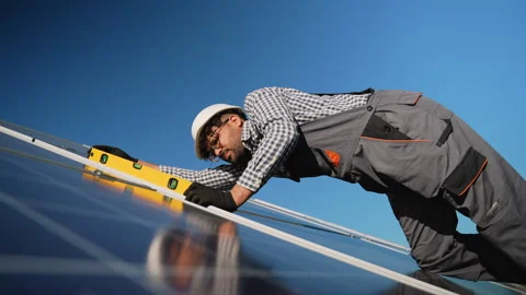 Middle eastern technician checking solar panel angle with spirit level on Stock Footage 314403500