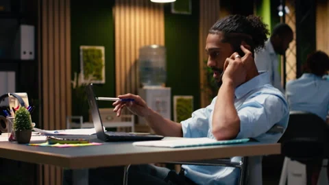 Middle Eastern wheelchair user engaged in phone call during office work Stock Footage 334042511