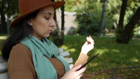 Middle Eastern woman reads e-book while sitting on a park bench. Using the Stock Footage 143321316